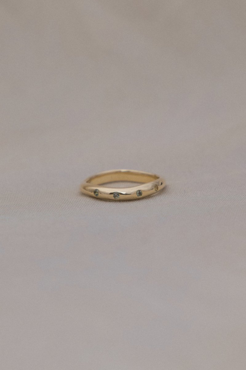 WAVY HANDCRAFTED SOLID GOLD RING FLUSH SET WITH FOUR GREEN SAPPHIRES